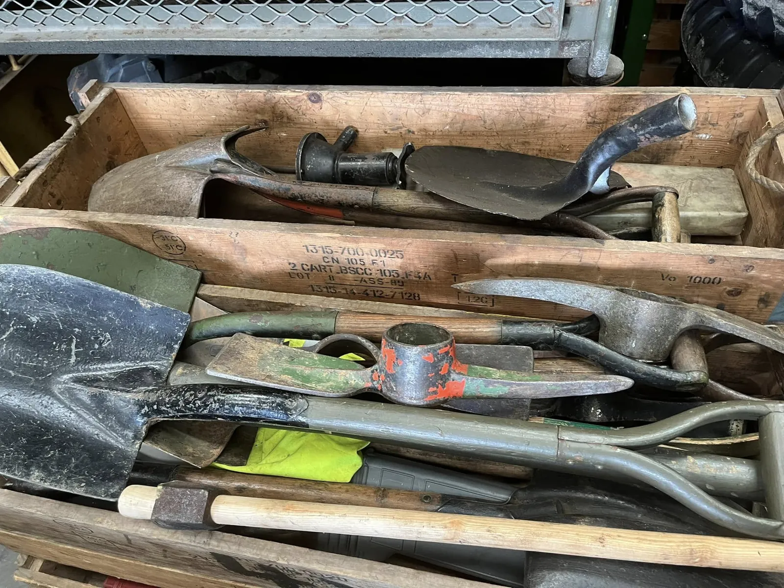 Caisse en bois remplie de pelles et de pioches militaires, manches en bois