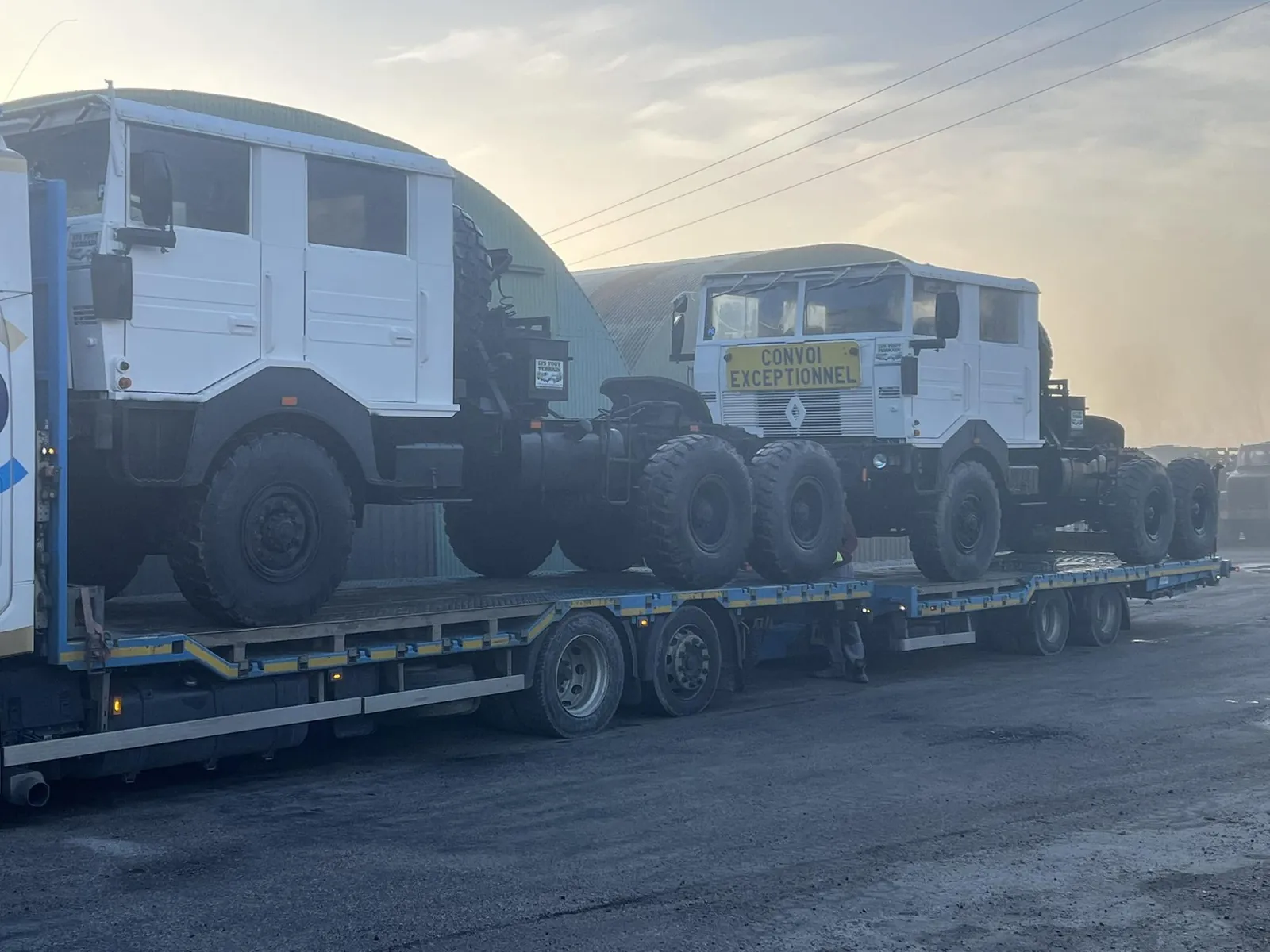 Deux tracteurs Renault 6x6 blancs sur porte-engins, panneau convoi exceptionnel à l’avant