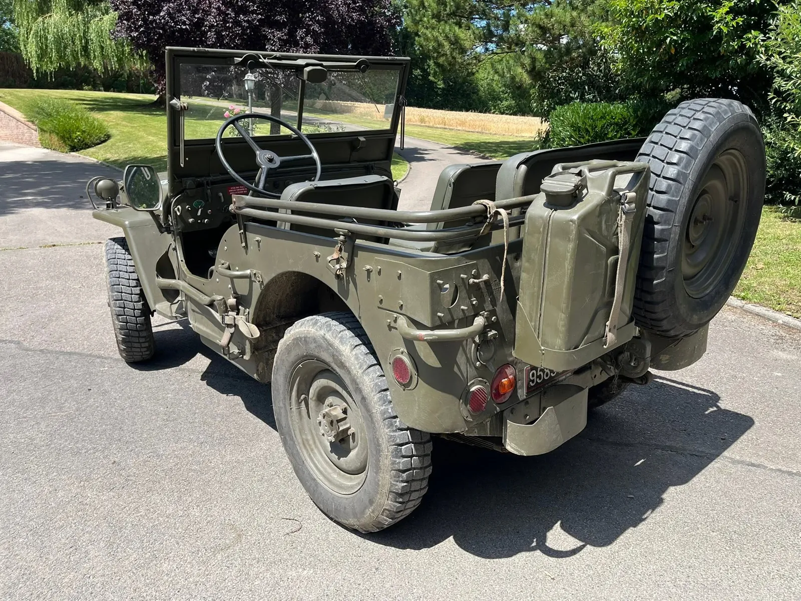 Jeep M201 vue de l’arrière : jerrican, roue de secours, sièges en skaï, pare-brise relevé