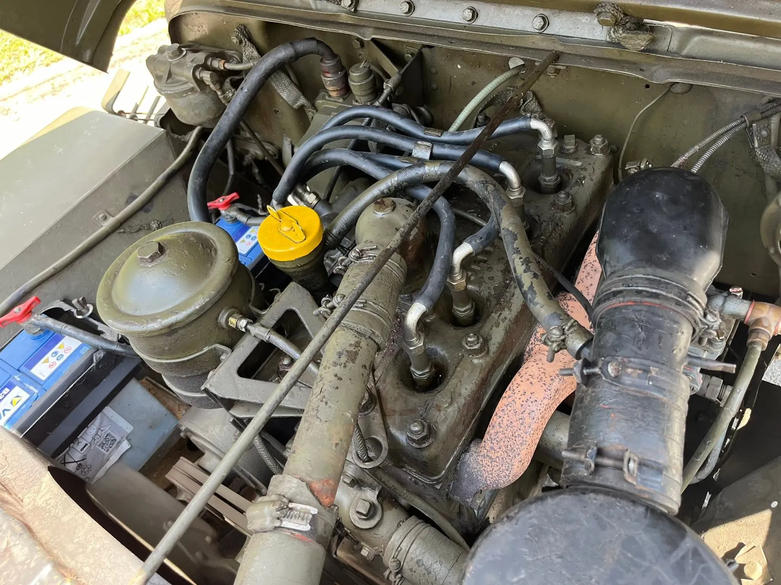 Moteur quatre cylindres de la Jeep M201, capot ouvert, filtre à air et deux batteries