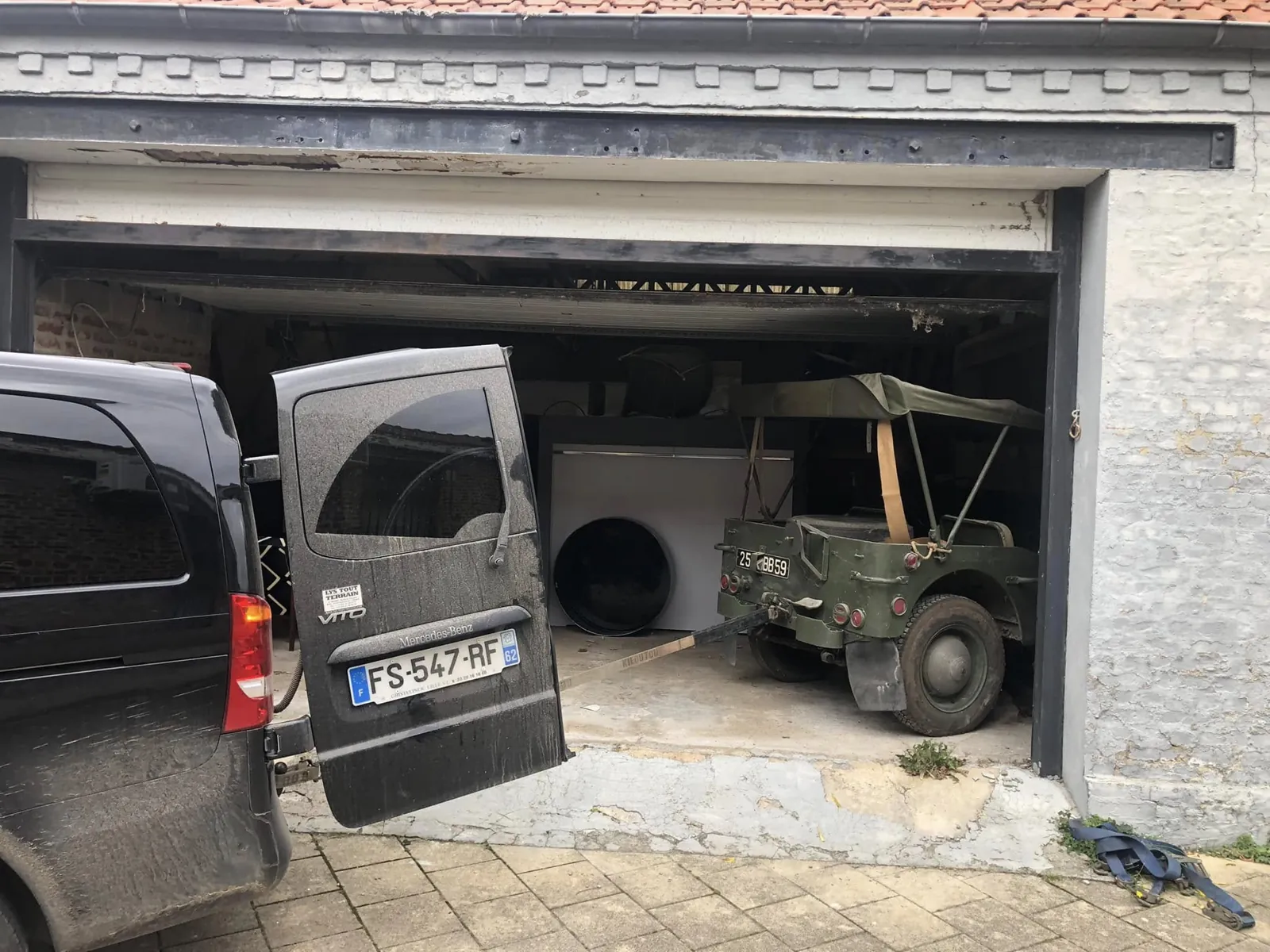 Ford GPW bâchée au fond d’un garage de Caudry, porte ouverte, fourgon devant