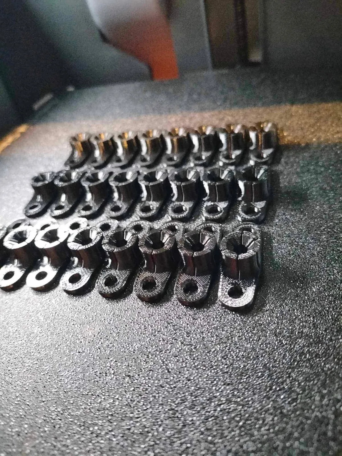 Lot d’agrafes de phare noires imprimées en 3D, alignées par rangées sur un plateau