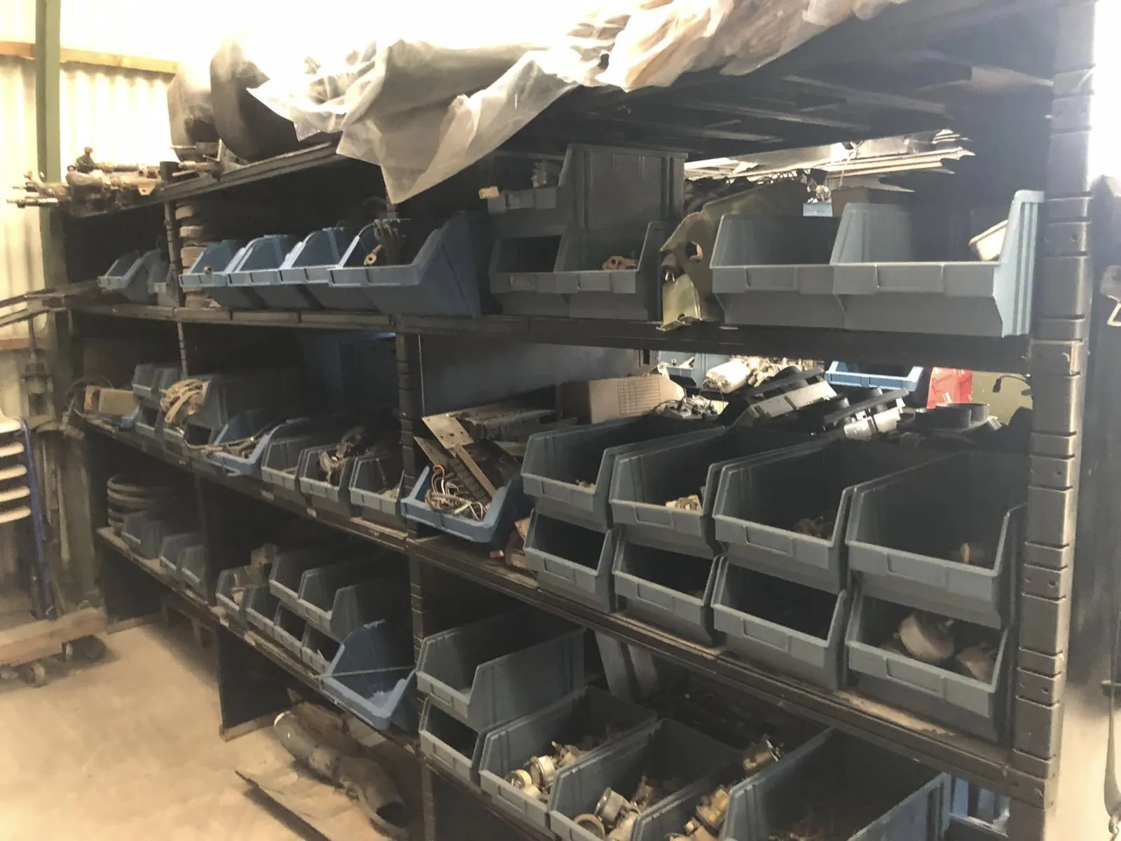 Rayonnage du magasin de pièces garni de bacs gris et bleus remplis de pièces d’occasion