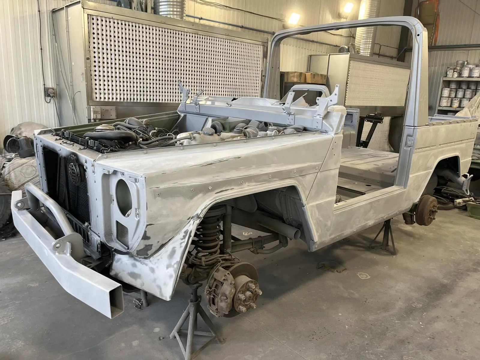 Caisse de Peugeot P4 en apprêt gris sur chandelles, ailes reprises, avant mise en peinture