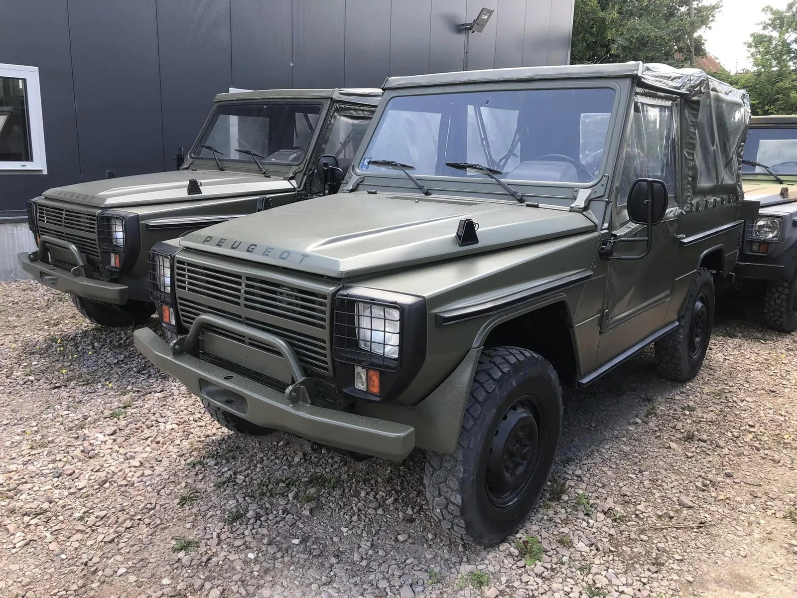 Peugeot P4 vert bâché garé sur le gravier, un second P4 vert en arrière-plan
