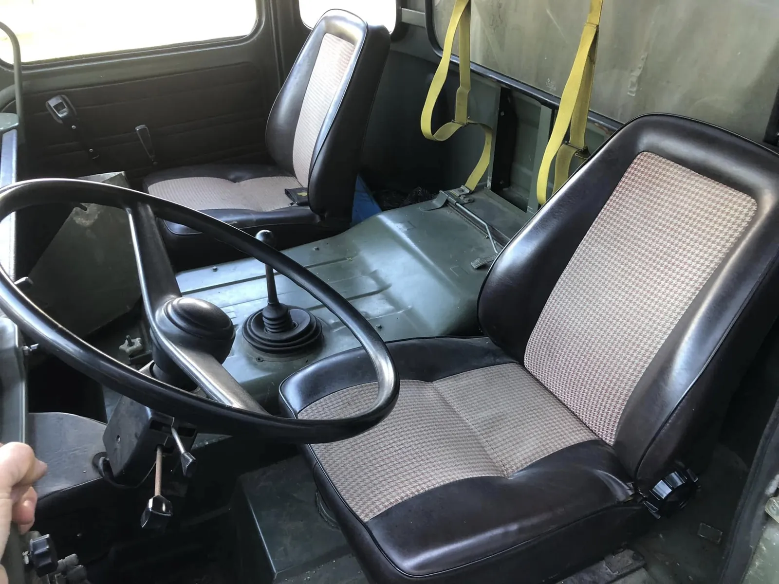 Cabine du TRM 4000 : sièges noirs à tissu pied-de-poule et levier au plancher